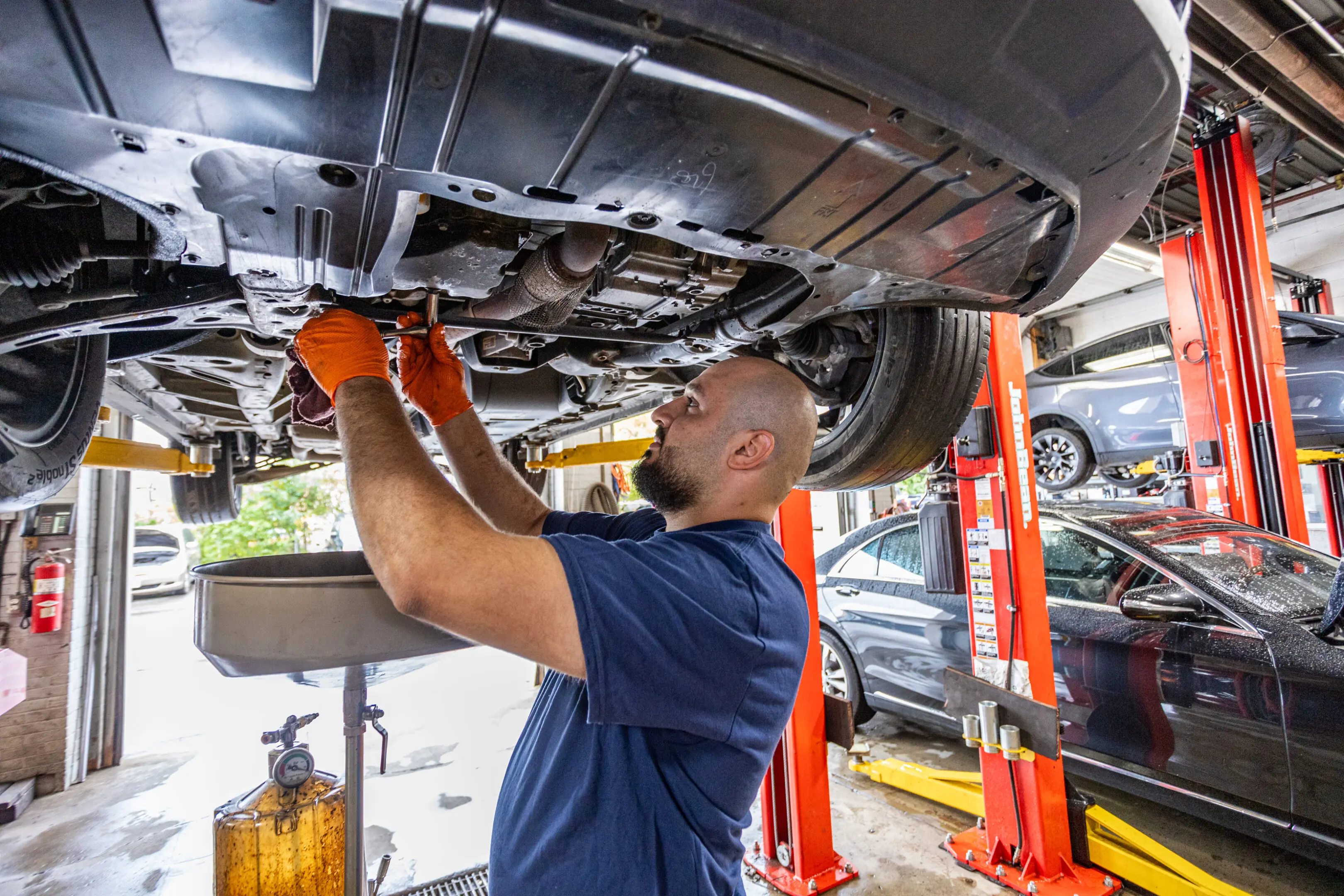 A man working on the underside of an automobile.